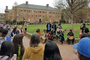 A group of people gather around students who are performing in UNC's quad.
