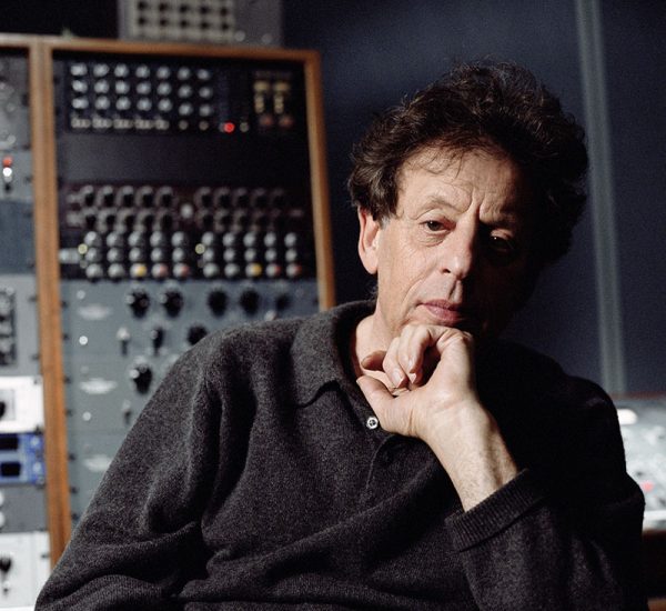 Philip Glass sits at a sound board.