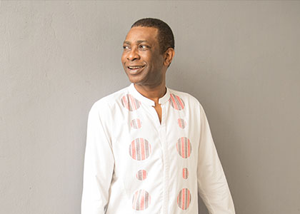 A man in white looks away from the camera, smiling.