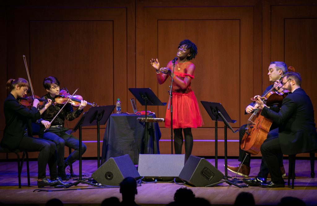 Woman in red singing with a string quartet