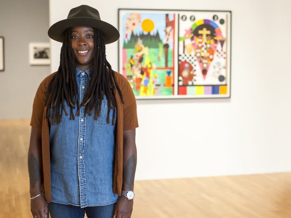 Artist Nina Chanel Abney stands in front of her artwork at a museum.