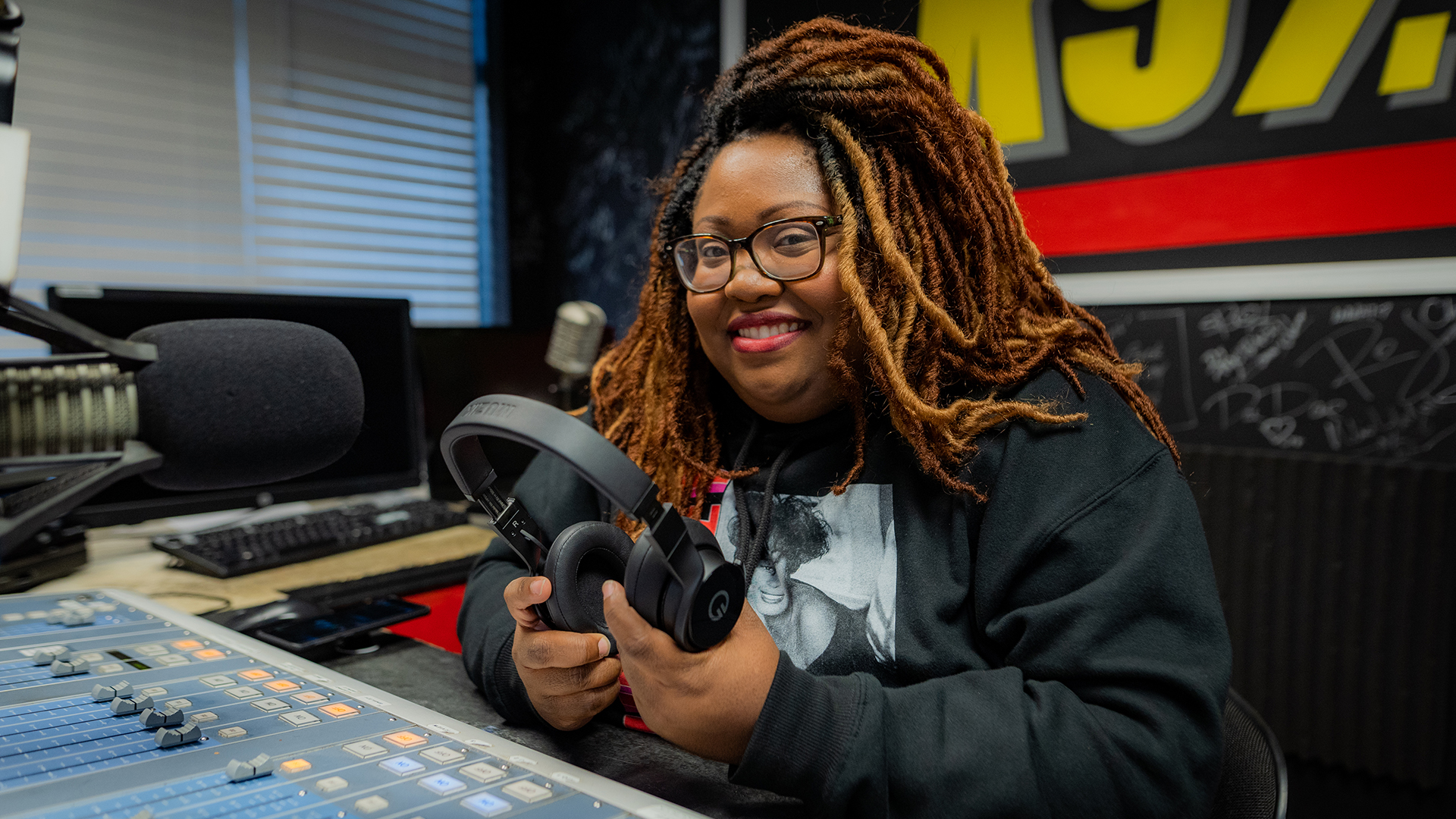 A woman poses with a microphone and headphones.