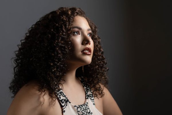 A woman with curly hair looks up, into the distance.